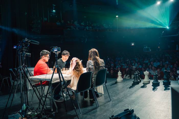 La scène vue de côté, joueurs à la table et public dans une lumière verte