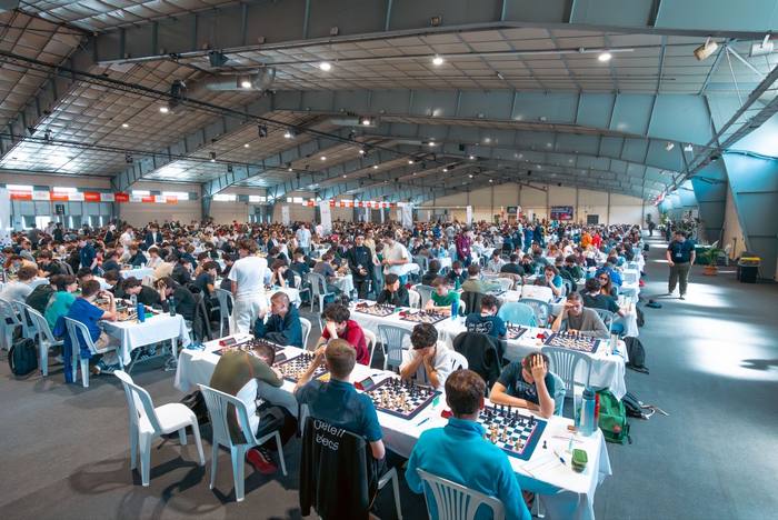Vue plongeante sur le hall du championnat, des centaines de tables blanches sous la charpente métallique