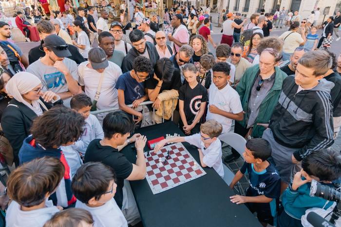 Simultanée de Julien Song dans la rue, foule serrée autour d’un échiquier mural