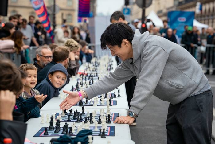 Julien Song joue une simultanée le long des tables installées dans la rue