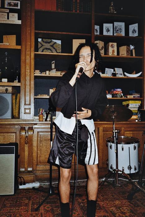 Chanteur en concert devant une bibliothèque, batterie au premier plan, photo argentique