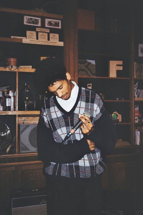 Chanteur en gilet à carreaux, tête baissée sur son micro entre deux couplets, photo argentique