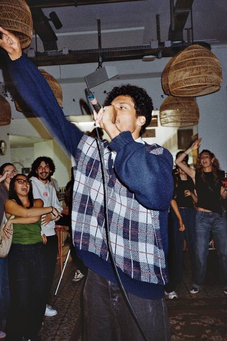 Chanteur bras levé au micro, entouré du public qui reprend en chœur, photo argentique