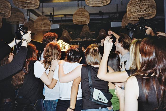 Le public de dos, bras levés vers l’enseigne lumineuse du fond de salle, photo argentique