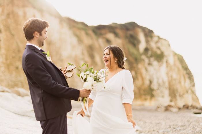 Photographie de mariage, les mariés riant au pied des falaises, lumière dorée
