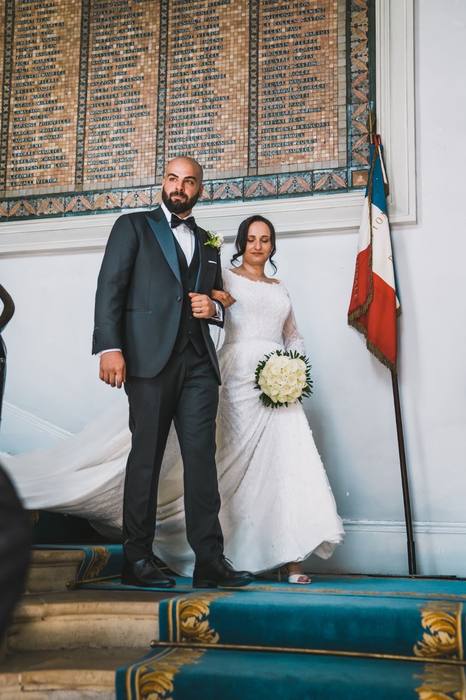 Les mariés descendant l’escalier de la mairie près du drapeau français
